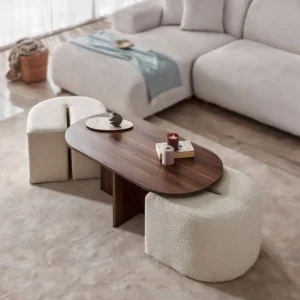 Black oval-style coffee table with two cream textured poufs tucked underneath in a neutral living room