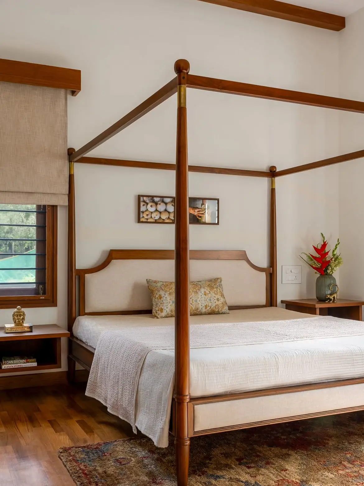 Brown full poster bed with four tall posts, overhead rails and a light upholstered headboard in a bedroom
