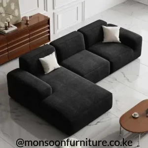 Dark charcoal modular sectional with three visible seating sections, broad padded arms and a low upholstered profile.