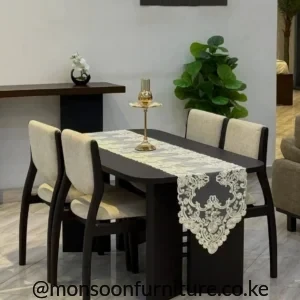 Compact dark Muninga dining table with four light upholstered chairs in a modern dining area in Kenya