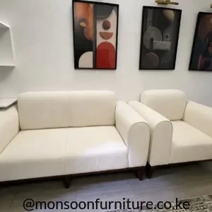 Cream upholstered sofa seating with broad rounded arms, padded backs and dark raised legs in a modern living room