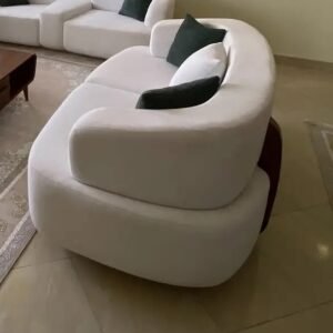 Cream curved modular sofa with rounded upholstered backs and dark contrasting cushions in a living room