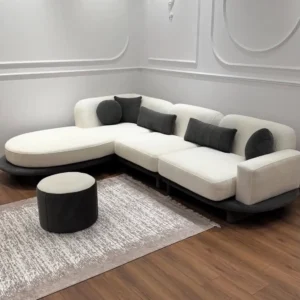 Cream curved sectional sofa with rounded chaise, dark base and contrasting dark cushions in a modern living room