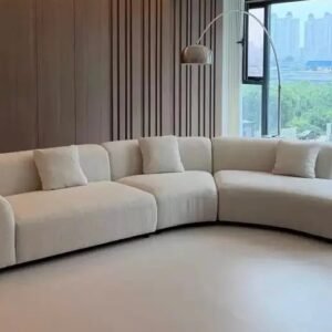 Cream modular sectional sofa with rounded arms, extended chaise and matching cushions in a modern living room