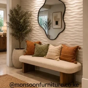 Cream textured upholstered ottoman bench with rounded ends and dark wood-finish supports in a neutral entryway.