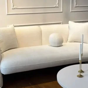 Cream rounded-arm sofa with square and round cushions in a light living room