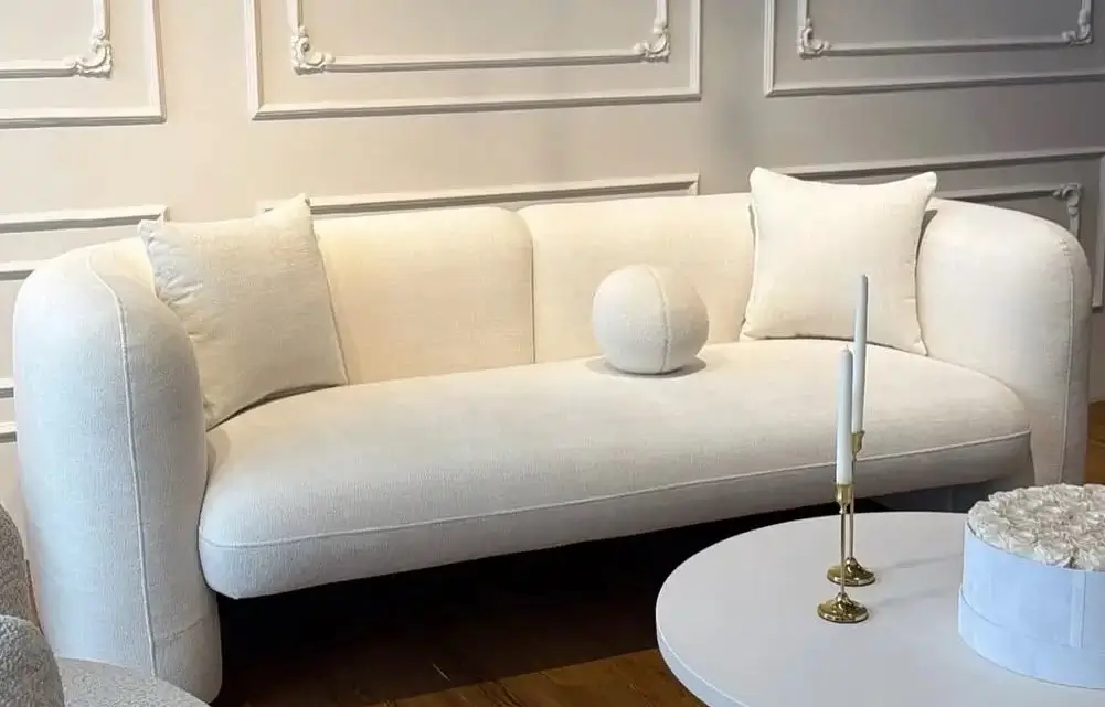 Cream rounded-arm sofa with square and round cushions in a light living room