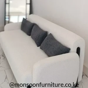 Cream textured sofa with rounded arms, charcoal cushions and exposed black legs in a bright living room