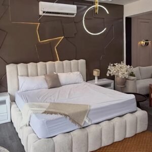 Cream upholstered bed with tall vertical padded headboard and matching segmented bed surround in a neutral bedroom