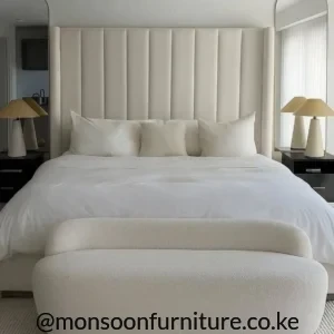 Cream upholstered bed with tall vertical panel headboard, white bedding and matching upholstered frame in a neutral bedroom.