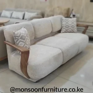Cream textured lounge sofa with divided back cushions, broad seating and curved warm wood-tone arm accents.