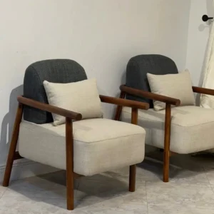 Two cream accent chairs with charcoal rounded backs, brown wooden-look frames and cream cushions.
