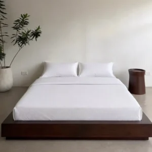 Dark brown low-profile platform bed with white mattress and bedding in a minimalist bedroom