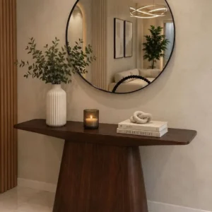 Dark brown curved entryway console beneath a large round black-framed mirror in a modern interior