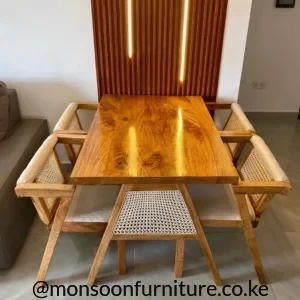 Rectangular warm wood-tone dining table with woven-back chairs and light neutral seat pads in a modern dining area.