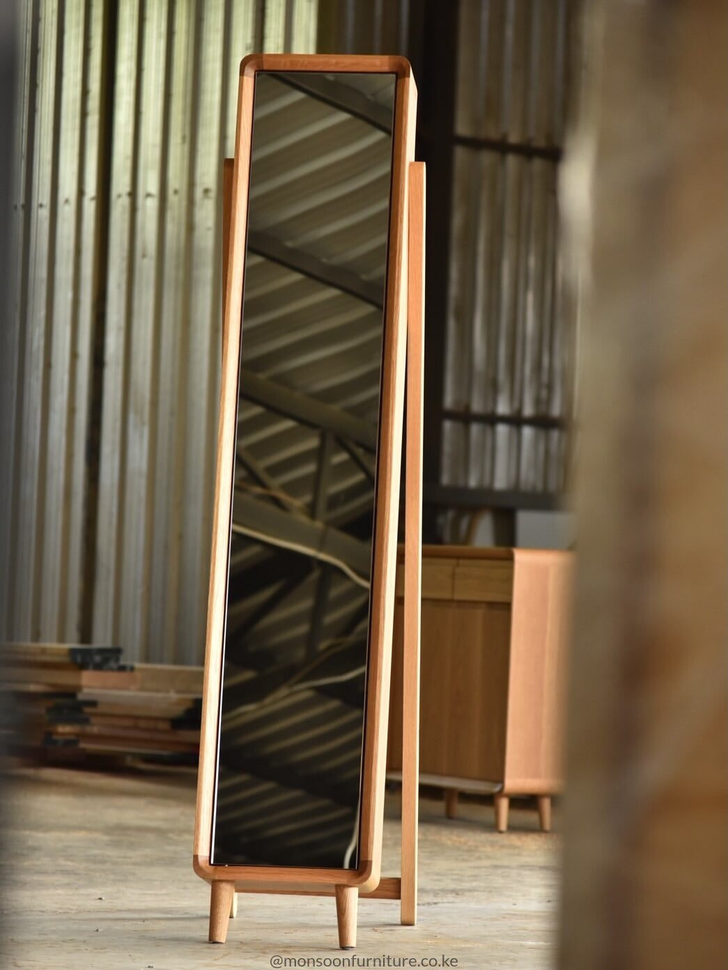 Tall freestanding dressing mirror with warm wood frame, two short front feet and a long rear support.