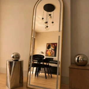 Gold arched full-length floor mirror with slim frame displayed against a neutral wall