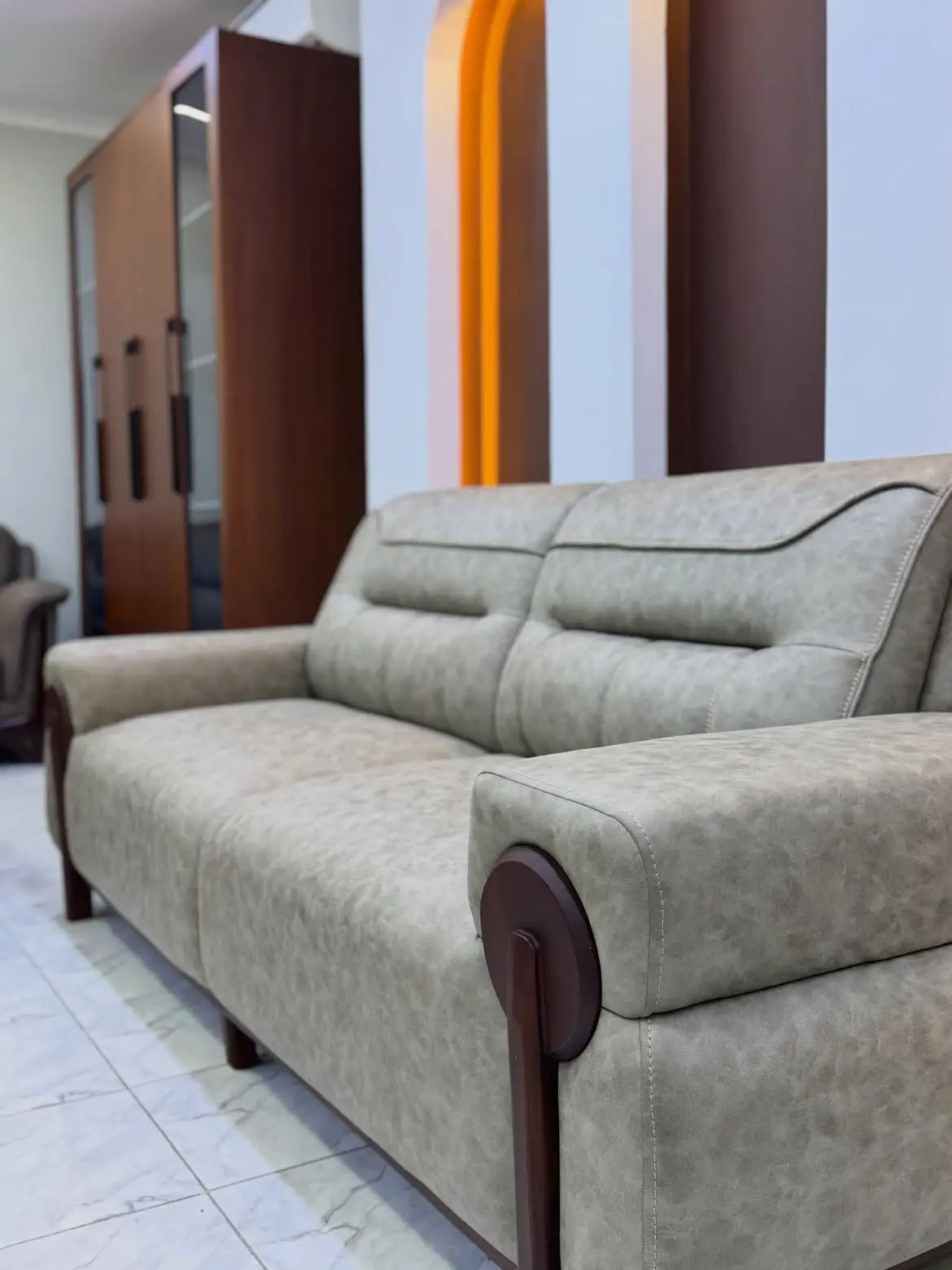 Light grey 5 seater sofa with cushioned backrests, broad arms and dark wood-tone side accents