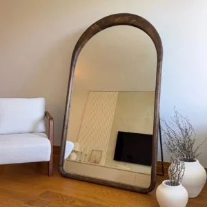 Mahogany arched floor mirror with dark brown wooden frame displayed in a living room