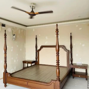 Mahogany four poster bed with tall turned posts, panelled footboard and light upholstered headboard in a bedroom