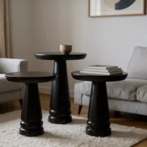 Three warm mahogany pedestal side tables with round tops arranged in a neutral living room