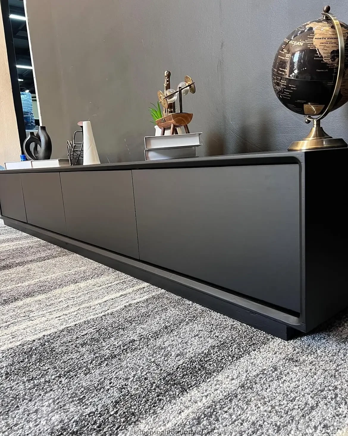 Matte black minimalist TV console with four clean-front cabinet doors in a contemporary living room