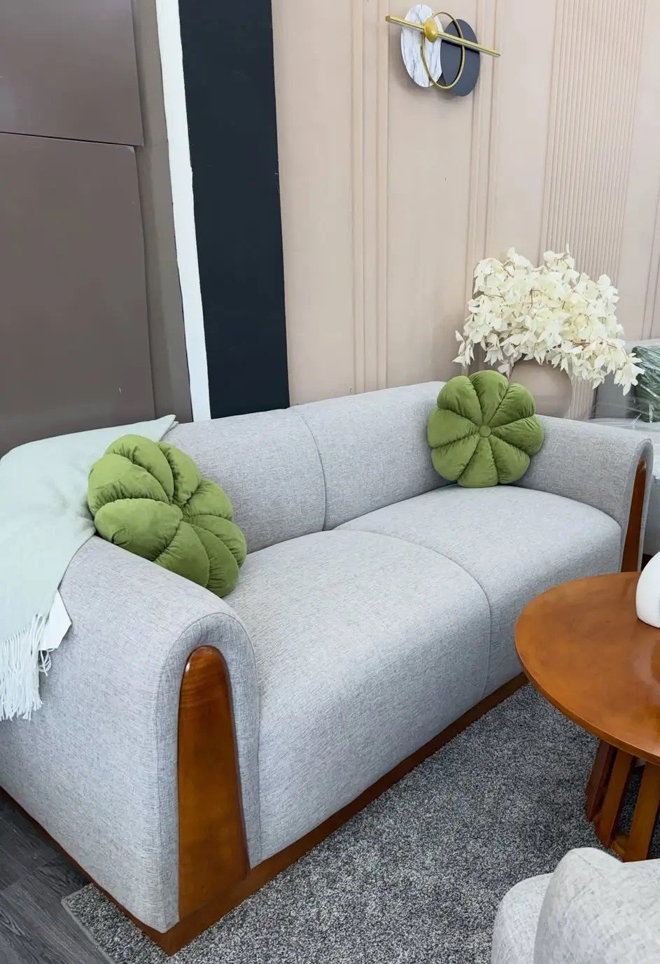Modern light-grey 3 seater sofa with rounded arms and contrasting wood-toned side accents in a furnished living room