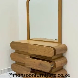 Muninga dressing table with a large framed mirror and six rounded warm-brown drawer fronts arranged in three tiers.