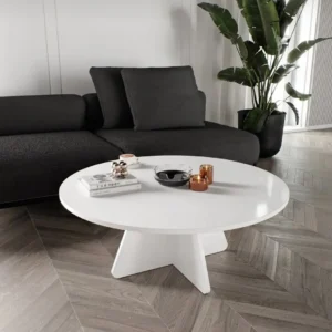 Round Mvule wood coffee table with natural grain and cross pedestal base in a modern living room