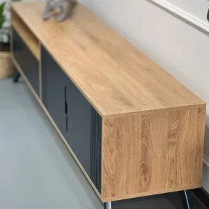 Natural wood-look TV console with black cabinet fronts, slatted detail and raised black legs