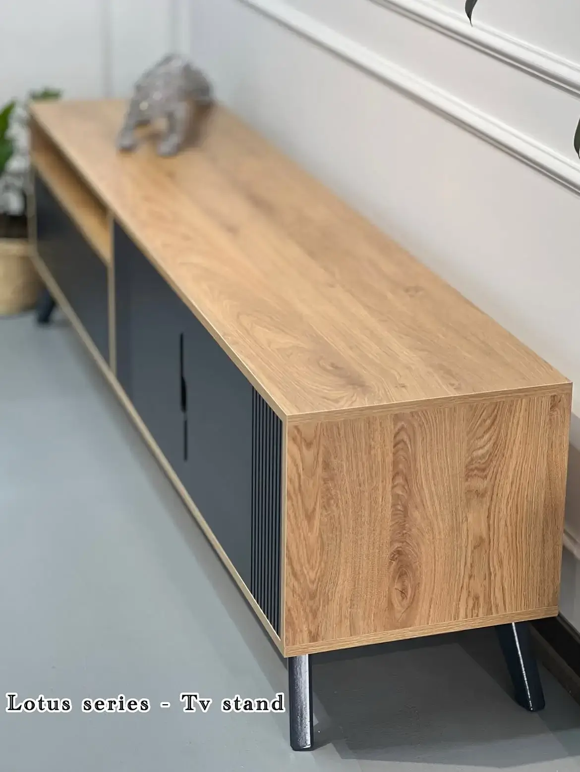 Natural wood-look TV console with black cabinet fronts, slatted detail and raised black legs