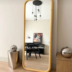 Tall full-length mirror with a warm brown wood-look frame and rounded corners in a neutral contemporary room