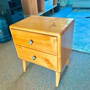Natural wood two-drawer bedside table with rounded edges, tapered legs and round metal-look knobs
