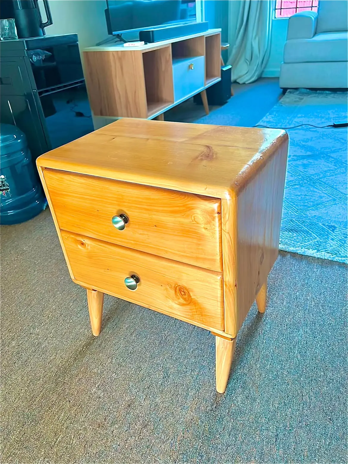 Natural wood two-drawer bedside table with rounded edges, tapered legs and round metal-look knobs