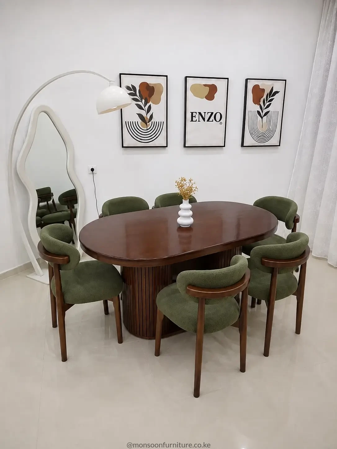 Oval dark brown dining table with ribbed pedestal base and six green upholstered dining chairs.