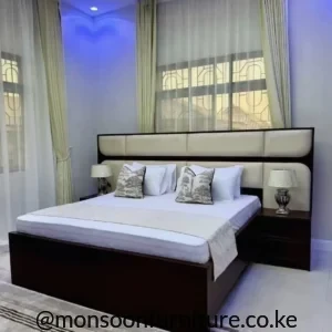 Dark brown bed with wide cream padded panel headboard, low frame and matching bedside cabinets in a bright bedroom.