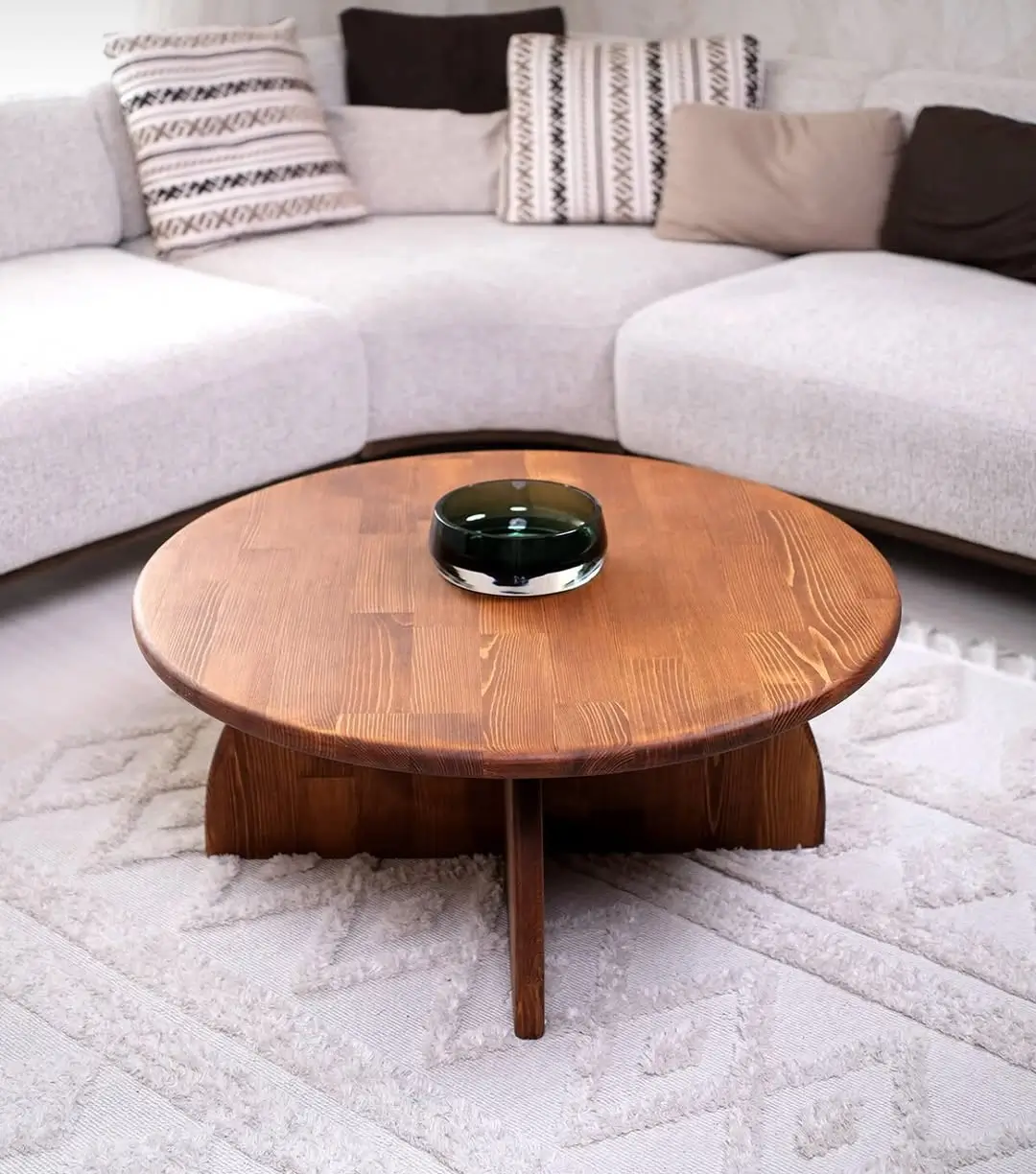 Round mahogany wood centre table with warm brown top and sculptural curved base in a modern living room