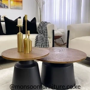 Two round nesting coffee tables with brown patterned tops and black pedestal bases in a cream living room