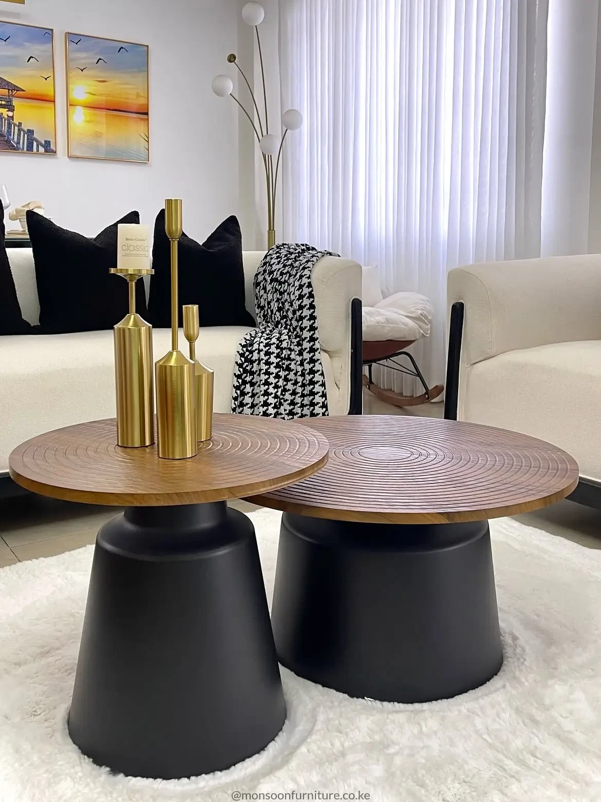 Two round nesting coffee tables with brown patterned tops and black pedestal bases in a cream living room