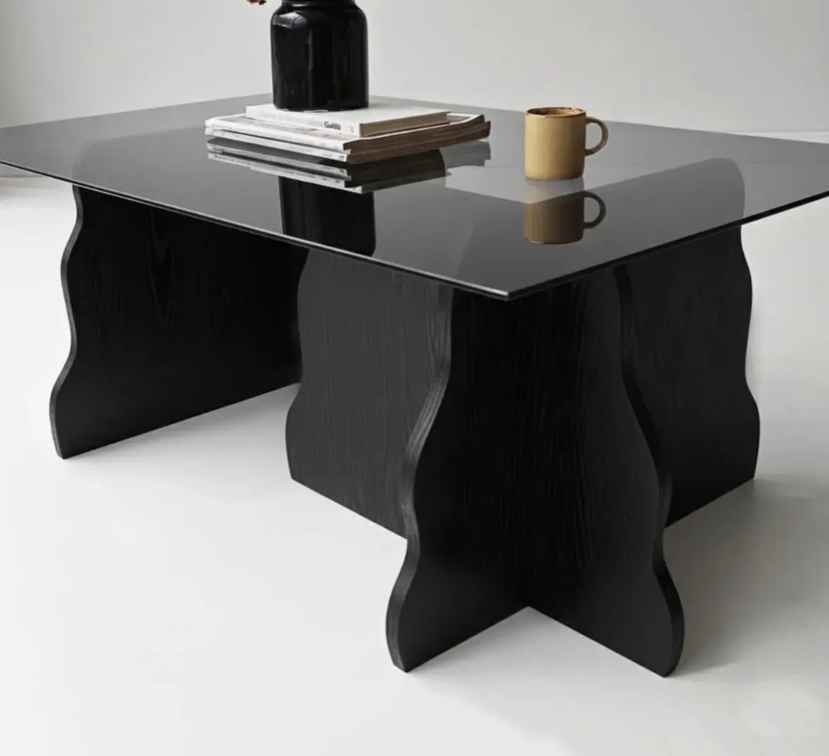 Sculptural glass top coffee table with four curved natural wood-look supports