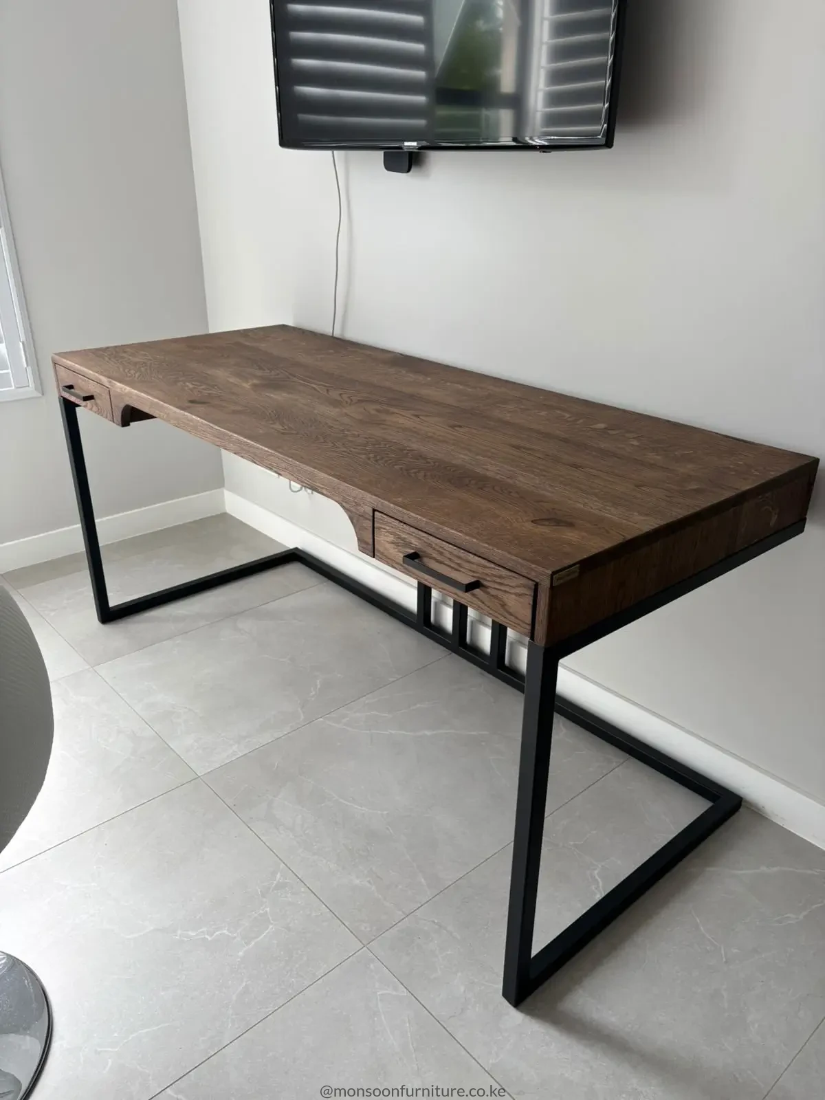 Solid oak desk with two drawers, natural brown wood grain and open black frame legs in a home office