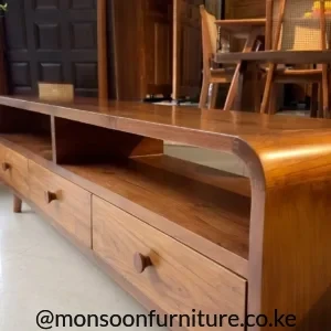Solid teak entertainment unit with rounded outer edges, open media shelves, lower drawers and sculpted wooden pulls.