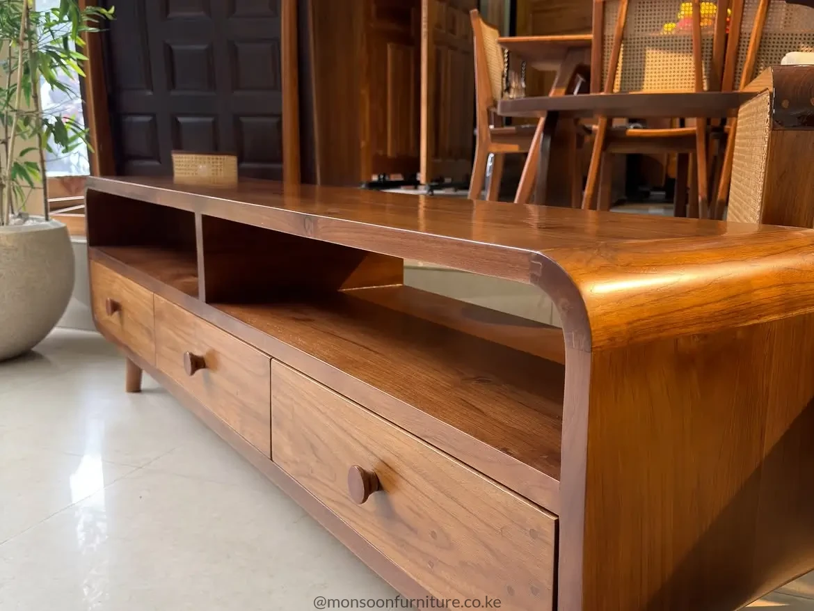 Solid teak entertainment unit with rounded outer edges, open media shelves, lower drawers and sculpted wooden pulls.