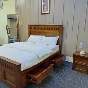 Walnut-look 5×6 panel bed with tall detailed headboard and matching footboard in a furnished bedroom