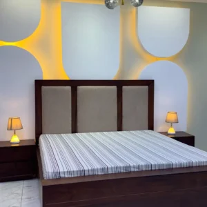 Walnut-tone 5×6 wooden bed with three-panel upholstered headboard and matching bedside tables