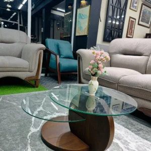 Walnut-tone coffee table with two offset transparent glass tops and curved dark brown base in a furnished living room