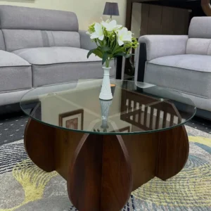 Round clear glass coffee table with dark walnut-look curved petal base in a grey sofa living room