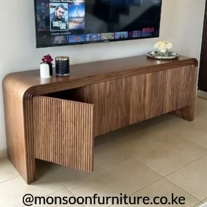 Walnut-brown slatted TV console with rounded ends and enclosed storage beneath a wall-mounted television