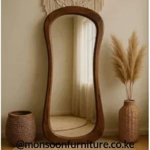 Warm brown full-length floor mirror with a softly irregular rounded frame leaning against a neutral wall