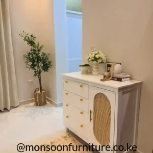 White storage chest with five drawers, gold-tone knobs and a cane-look side cabinet door.